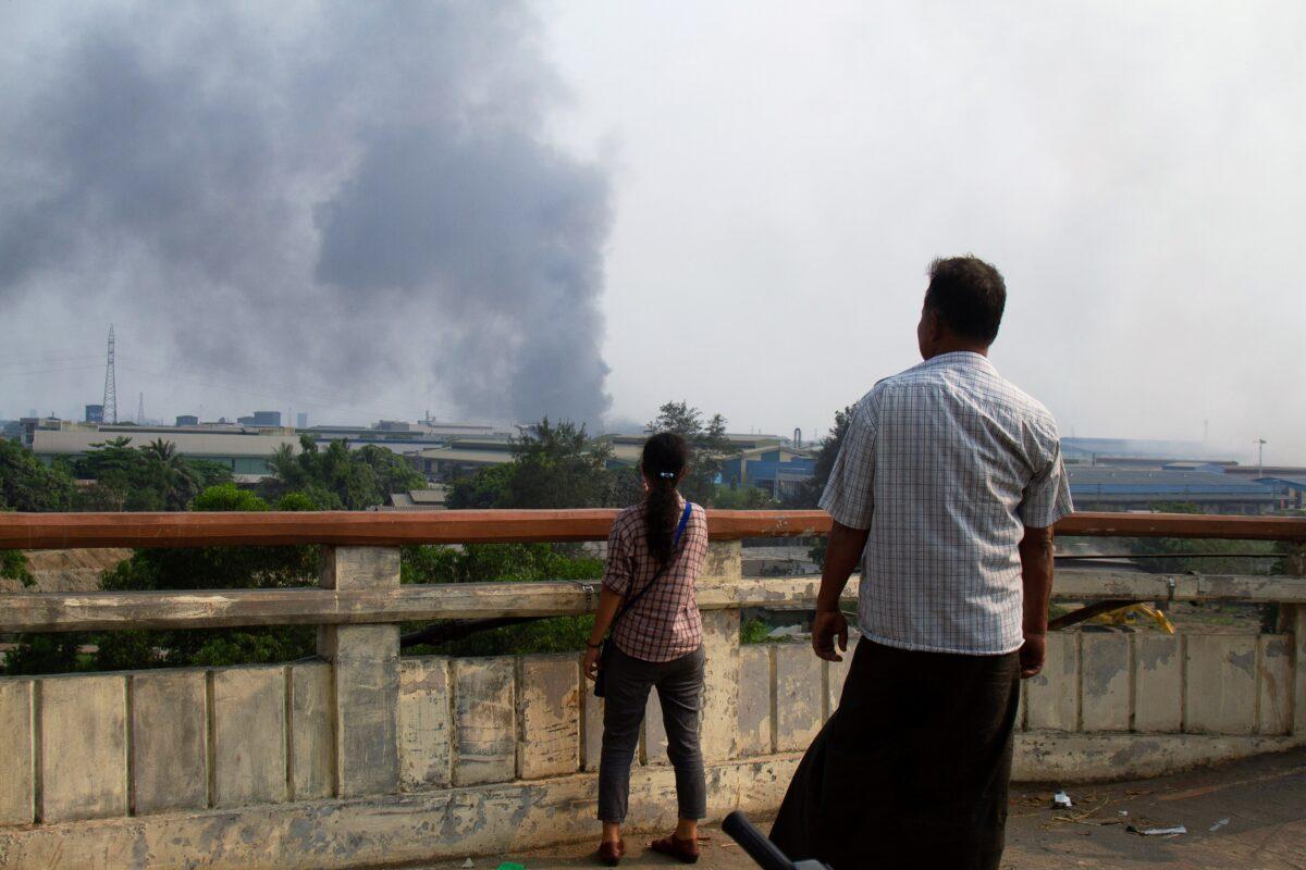 People look at smoke believed to be from a factory fire during the security force crack down on anti-coup protesters at Hlaingthaya, Yangon, Burma, on March 14, 2021. (Stringer/Reuters)