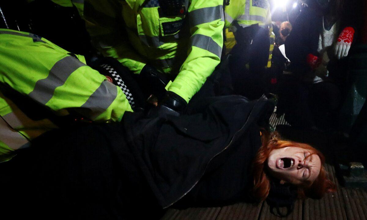 Police detain Patsy Stevenson as people gather at a memorial site in Clapham Common Bandstand following the alleged kidnap and murder of Sarah Everard, despite a ban on gatherings due to the CCP virus restrictions, in London, on March 13, 2021. (Hannah McKay/Reuters)