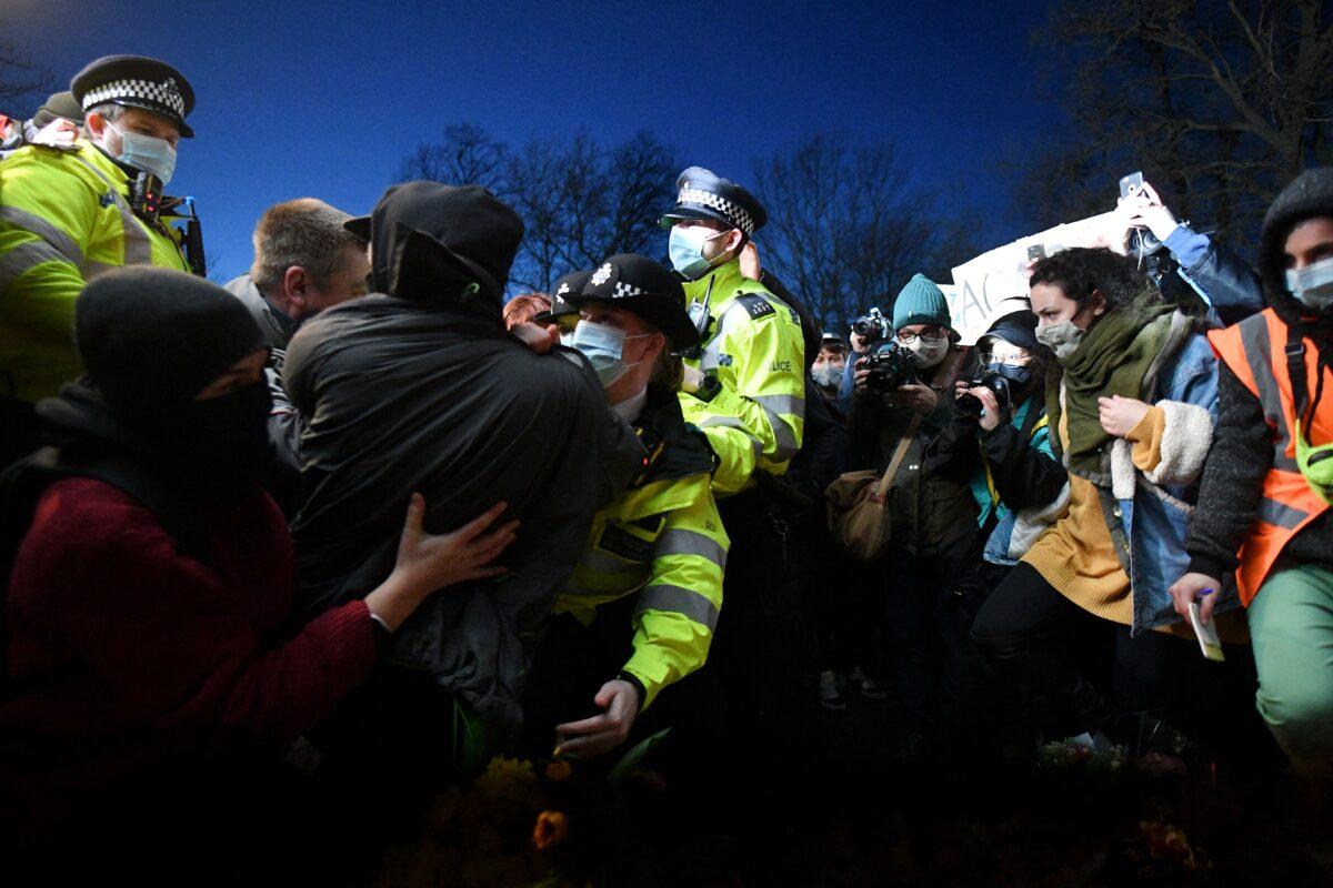 Police officers scuffle with people gathering at a band-stand where a planned vigil in honour of alleged murder victim Sarah Everard was cancelled due to Covid-19 restrictions, on Clapham Common, south London on March 13, 2021. (Justin Tallis/AFP via Getty Images)