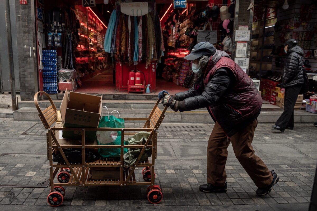 An elderly woman pushes a cart along a street near the Great Hall of the People in Beijing, China on March 5, 2021. (Nicolas Asfouri/AFP via Getty Images)