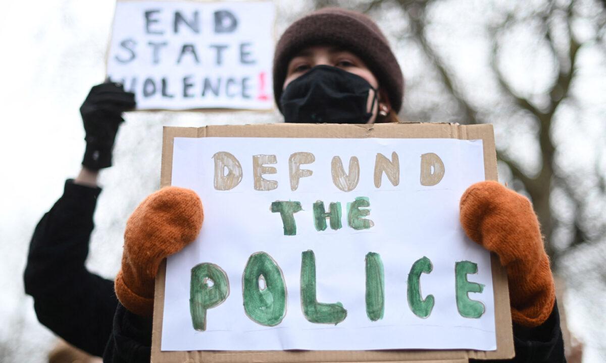 Protesters holding signing reading "DEFUND THE POLICE" and "END STATE VIOLENCE" after the death of Sarah Everard, who was allegedly kidnapped and murdered by a police officer, outside New Scotland Yard, the headquarters of the Metropolitan Police Service, in London on March 14, 2021. (Daniel Leal-Olivas/AFP via Getty Images)