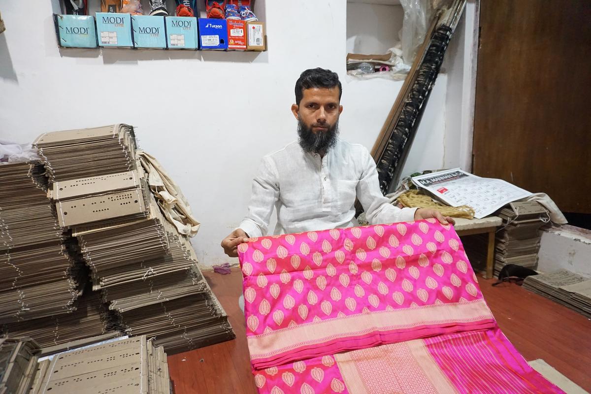 Meeraz Akhtar, 40, a master saree weaver, sits in his handloom unit showcasing a Banarasi silk saree. The pink, or base, silk in this saree is from China, while the golden silk is Indian. (Venus Upadhayaya/Epoch Times)
