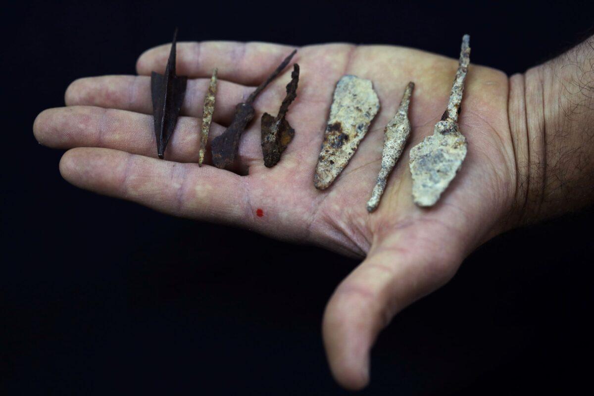An employee holds ancient arrow and spearheads, part of various artifacts recently discovered in the Judean Desert caves, during an unveiling event for media at Israel Antiquities Authority laboratories in Jerusalem, Israel, on March 16, 2021. (Ammar Awad/Reuters)