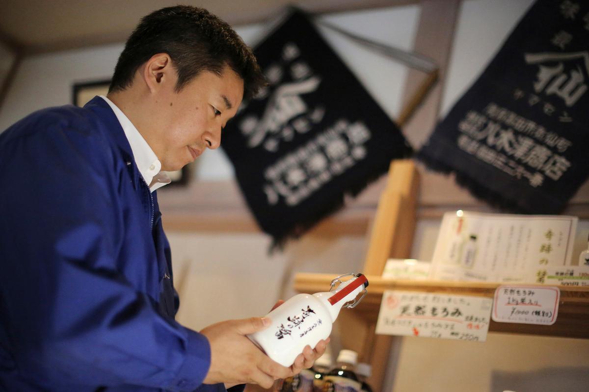 Michihiro Kono, president of Yagisawa Shoten Co., holds his company's soy sauce bottle, named "the miracle," at his company's new headquarters in Rikuzentakata, Iwate Prefecture, northeastern Japan. (Eugene Hoshiko/AP)