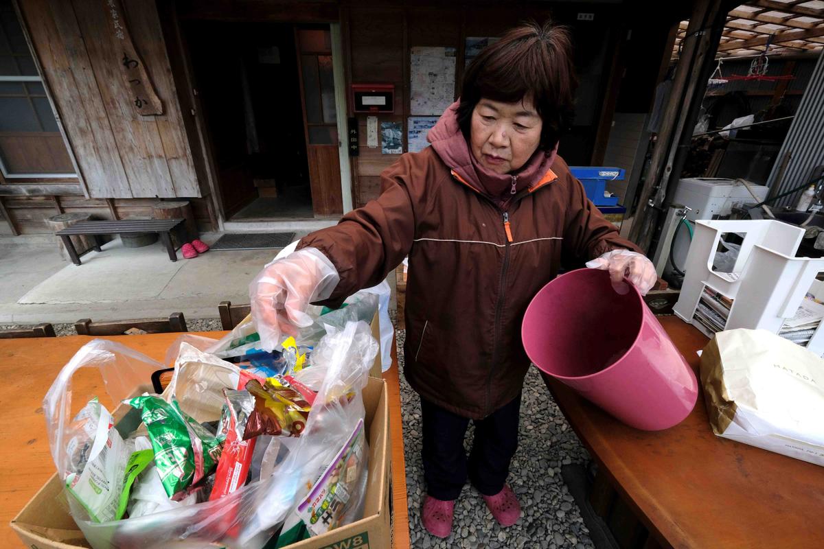 Japanese resident Saeko Takahashi sorting trash into a box at her home in the town of Kamikatsu, Tokushima prefecture (KAZUHIRO NOGI/AFP via Getty Images)