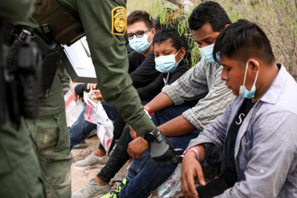 A Border Patrol agent checks an illegal immigrant wearing two wristbands that Mexican cartels have been using to control human smuggling into the United States, near Penitas, Texas, on March 15, 2021. (Charlotte Cuthbertson/The Epoch Times)