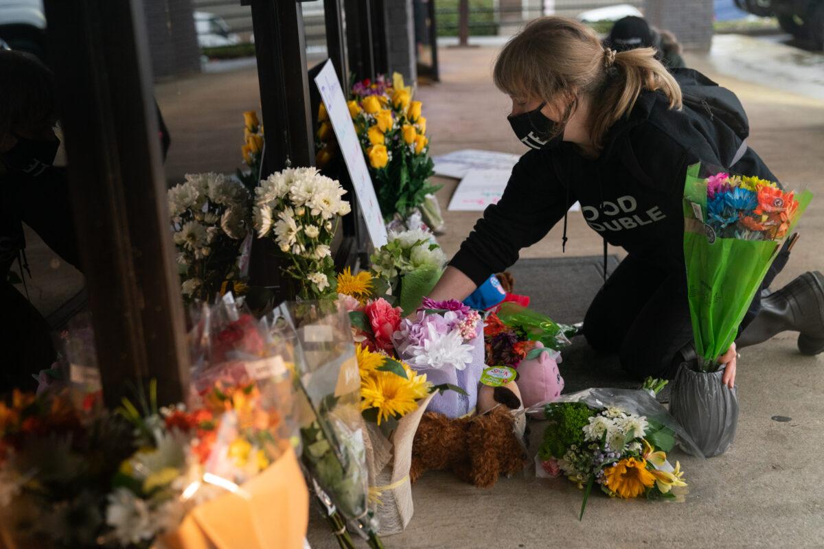 Shelby Swan adjusts flowers and signs outside Youngs Asian Massage where four people were shot and killed, in Acworth, Ga., on March 17, 2021. (Elijah Nouvelage/Getty Images)