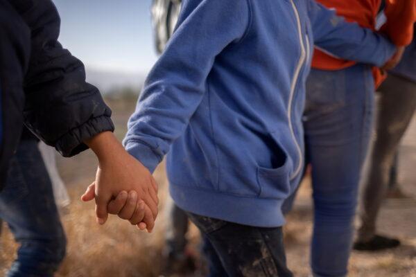 Unaccompanied minors hold hands amid adult migrants from Central America as they await transport after crossing the Rio Grande river into the United States from Mexico on a raft in Penitas, Texas, on March 12, 2021. (Adrees Latif/Reuters)
