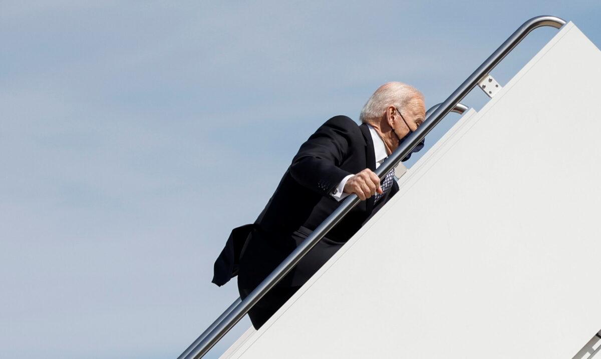 President Joe Biden hangs onto the railing with one hand as he stumbles while climbing the steps of Air Force One while departing Washington for travel to Atlanta, Georgia at Joint Base Andrews, Md., on March 19, 2021. (Carlos Barria/Reuters)