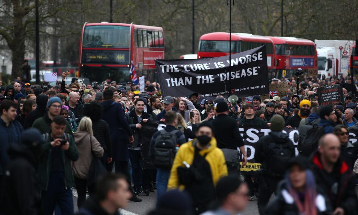 Protesters carry a sign saying "The 'cure' is worse than the 'disease'" as they march during a anti-lockdown protest in London on March 20, 2021. (Hollie Adams/Getty Images)