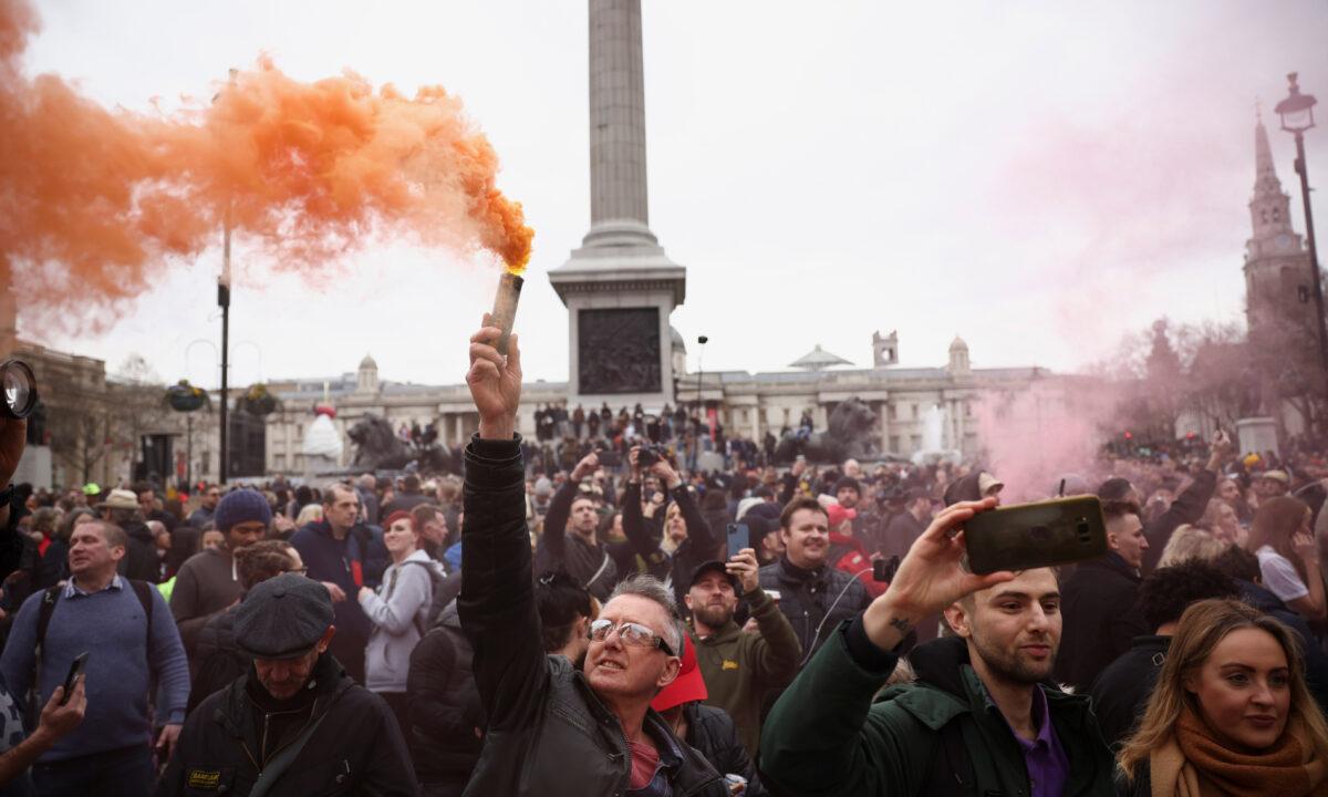 A person holds a colour smoke bomb during a protest against CCP virus lockdown in London, on March 20, 2021. (Henry Nicholls/Reuters)