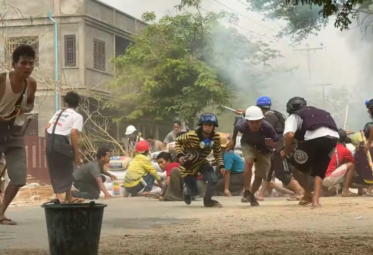 Protesters take cover during clashes with security forces in Monywa, Burma, on March 21, 2021. (Still image from a video obtained by Reuters)