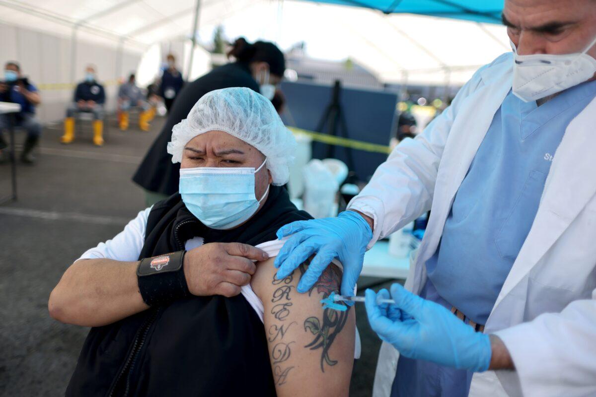 Delores Renteria, 54, receives a COVID-19 vaccination at a mobile vaccination drive for essential food processing workers at Rose & Shore, Inc., in Los Angeles on March 17, 2021. (Lucy Nicholson/Reuters)