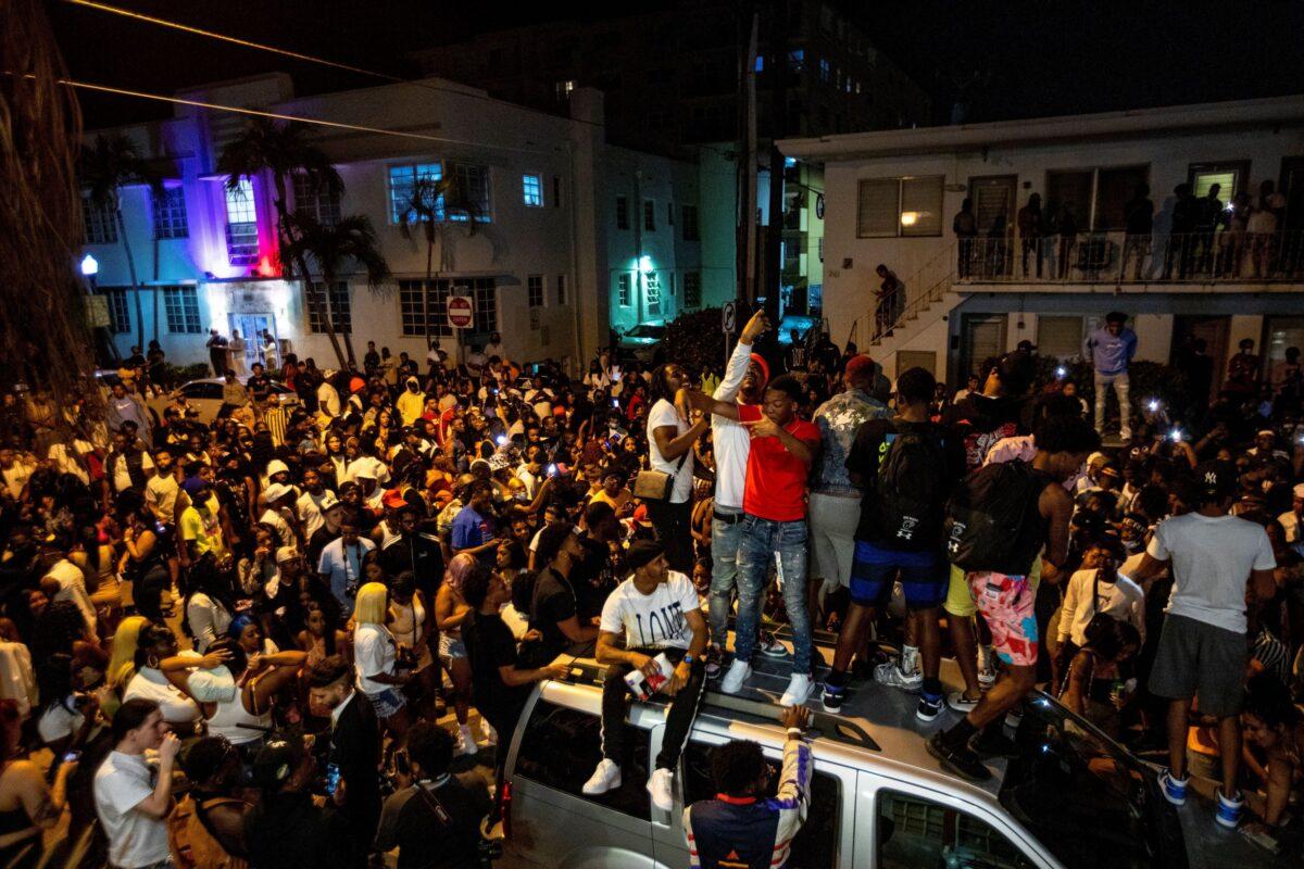Crowds defiantly gather in the street while a speaker blasts music an hour past curfew in Miami Beach, Fla., on March 21, 2021. (Daniel A. Varela/Miami Herald via AP)