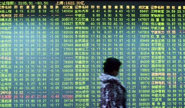 An investor walks past a screen showing stock market movements at a securities firm in Hangzhou, China, on Jan. 11, 2016. (STR/AFP via Getty Images)