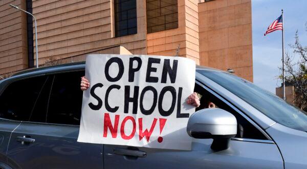 Signs calling for schools to reopen are displayed by people in passing vehicles during an "Open Schools Now" rally in Los Angeles on Feb. 15, 2021. (Frederic J. Brown/AFP via Getty Images)