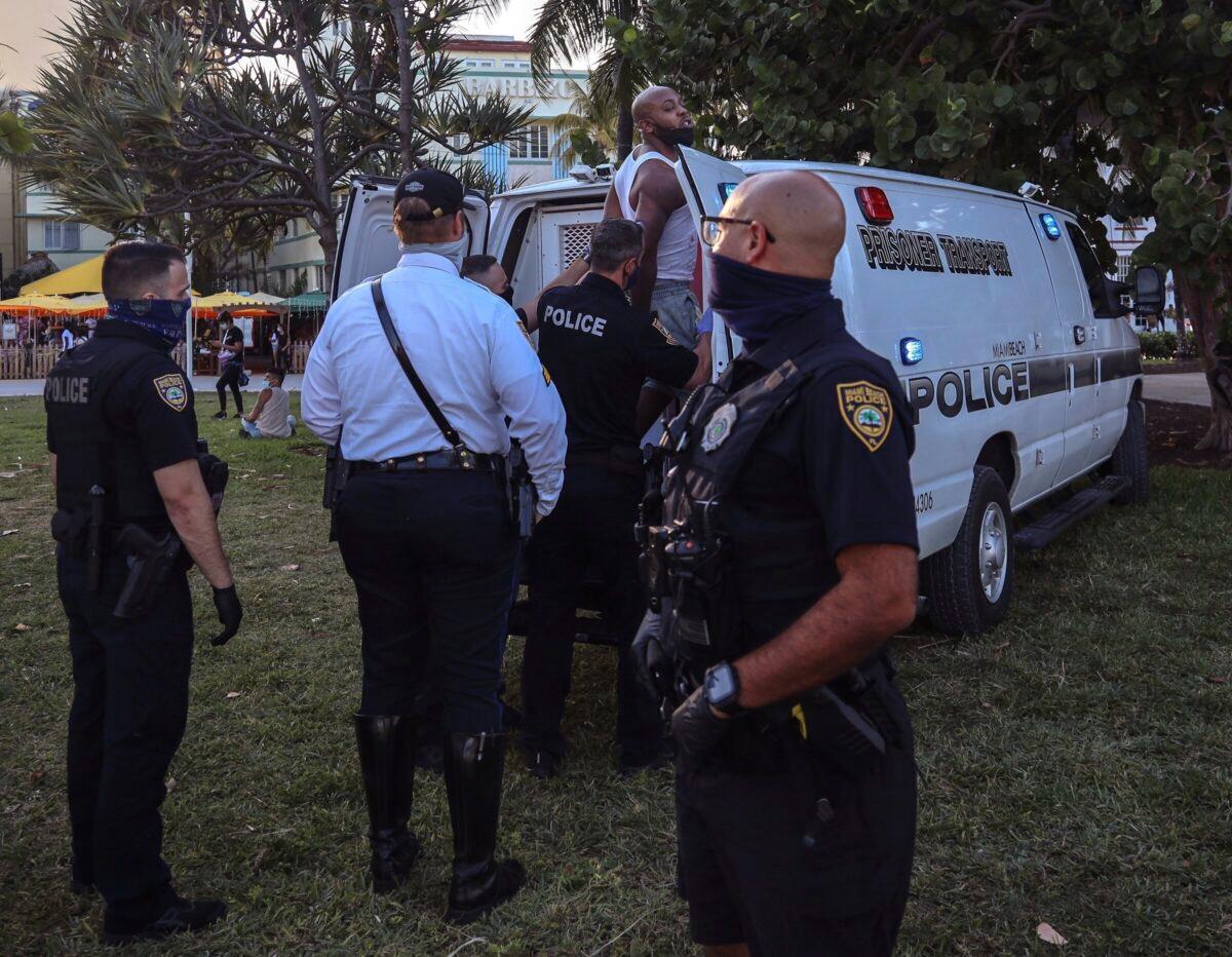 An unidentified man is detained and later arrested at 5th Street and Ocean Drive in Miami Beach, Fla., on March 21, 2021. (Carl Juste/Miami Herald via AP)