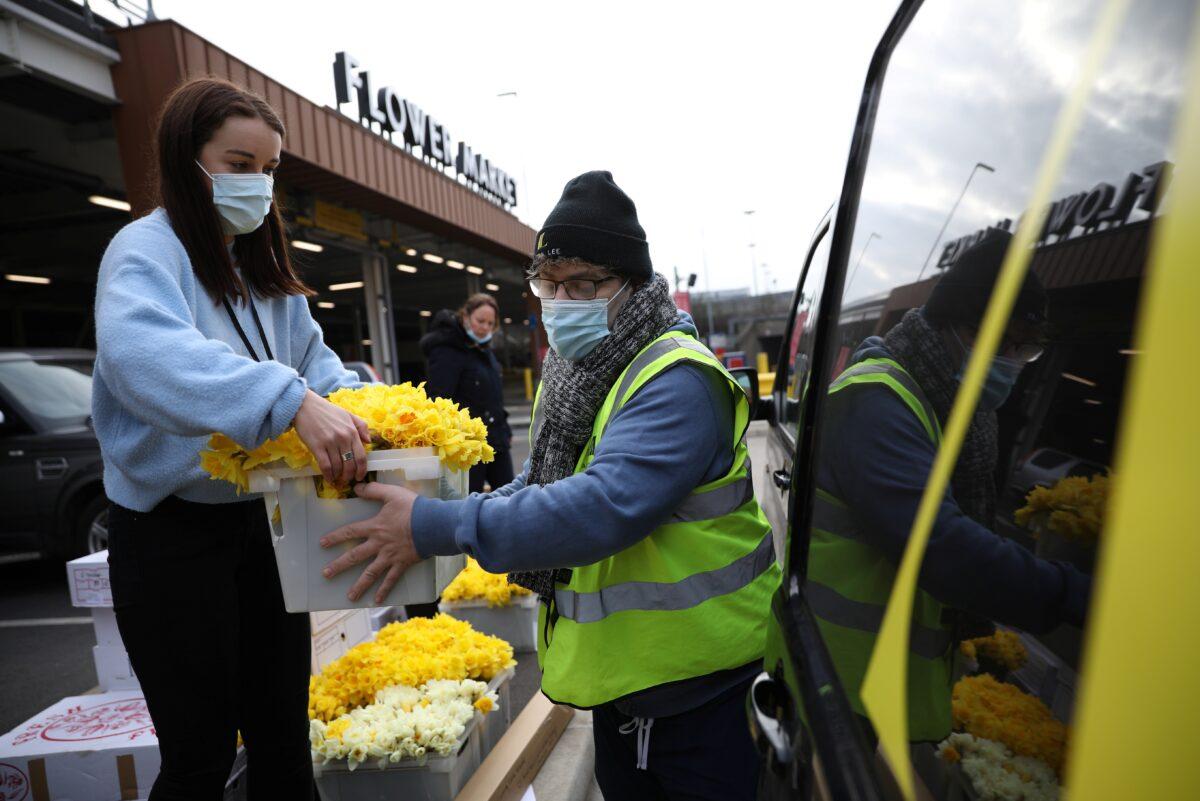 Cassie Burt, marketing and communications manager of Covent Garden Market Authority, receives an order of flowers outside the New Coven Garden Flower Market, during the day of reflection to mark the anniversary of Britain's first coronavirus disease (COVID-19) lockdown, in London, Britain, on March 23, 2021. (Tom Nicholson/Reuters)