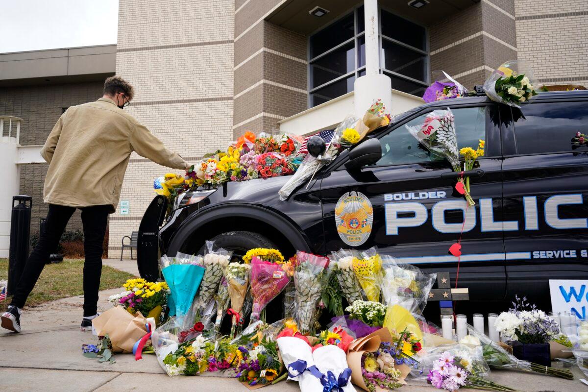 A man leaves a bouquet on a police cruiser parked outside the Boulder Police Department after an officer was one of the victims of a mass shooting at a King Soopers grocery store, in Boulder, Colo., on March 23, 2021. (David Zalubowski/AP Photo)
