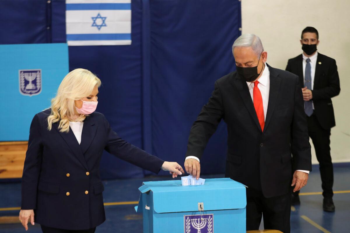 Israeli Prime Minister Benjamin Netanyahu and his wife Sara cast their ballots at a polling station as Israelis vote in a general election, in Jerusalem, on March 23, 2021. (Ronen Zvulun/Pool via AP)