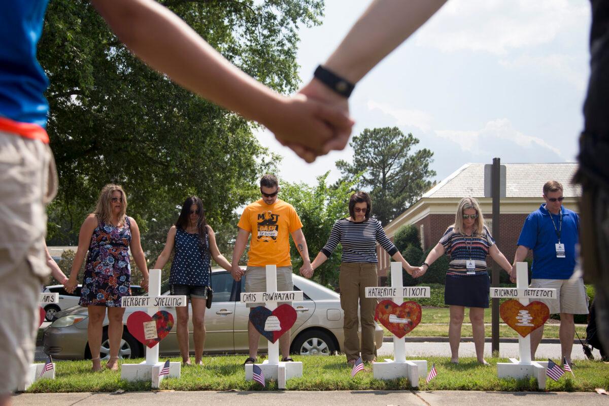 Community members hold hands and pray around a memorial to honor those killed in a mass shooting that took place at the Virginia Beach Municipal Center days earlier, in Virginia Beach, Va. on June 2, 2019. (Sarah Holm/The Virginian-Pilot via AP)