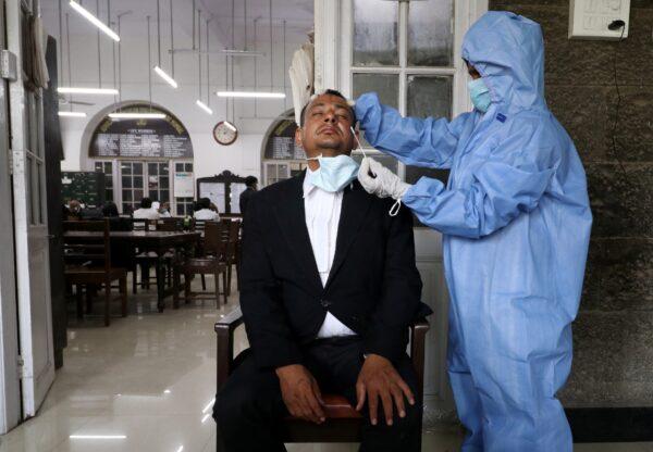 A health care worker collects a swab sample from a court employee during a rapid antigen testing campaign for COVID-19, at a court in Mumbai, India, on March 25, 2021. (Niharika Kulkarni/Reuters)