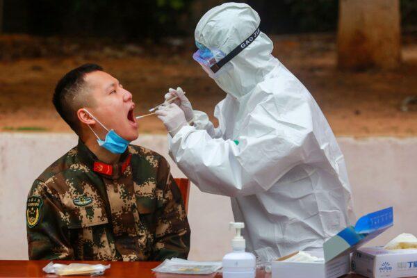 A medical staff member tests a paramilitary police officer for COVID-19 in Shenzhen, China, on Feb. 11, 2020. (STR/AFP via Getty Images)