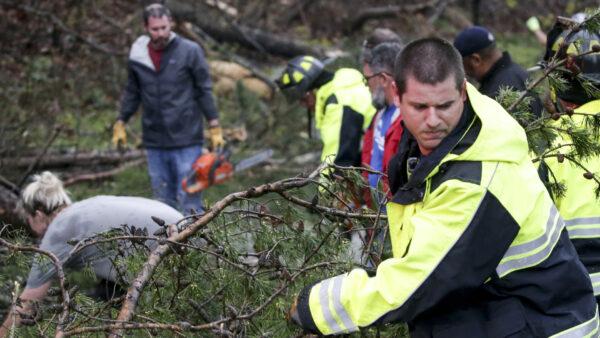A firefighter works with residents to remove fallen trees blocking roads for rescue crews to get past after a tornado touched down south of Birmingham, Ala. in the Eagle Point community damaging multiple homes on March 25, 2021. (Butch Dill/AP Photo)