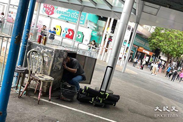 In this undated photo, a man takes out poster displays that slander Falun Gong from a steel cabinet which is believed to belong to the HKYCA and is bound to a pier at Tsim Sha Tsui in Hong Kong. (Provided to The Epoch Times)