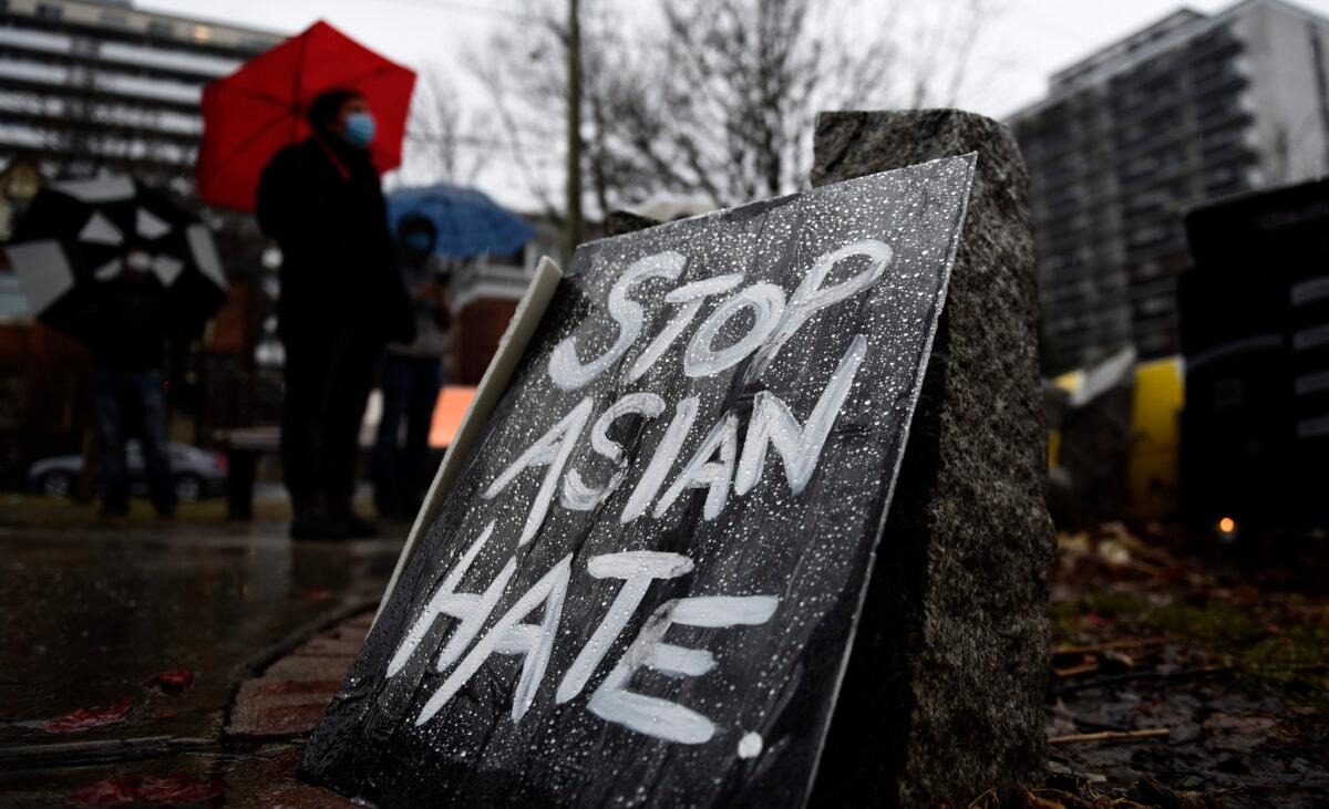 Rain beads on a sign as community members gather at the Ottawa Women's Monument in Minto Park for a vigil in memory of the victims of the Atlanta spa shootings and to rally against anti-Asian racism, in Ottawa, on Sunday, March 28, 2021. (Justin Tang/The Canadian Press)