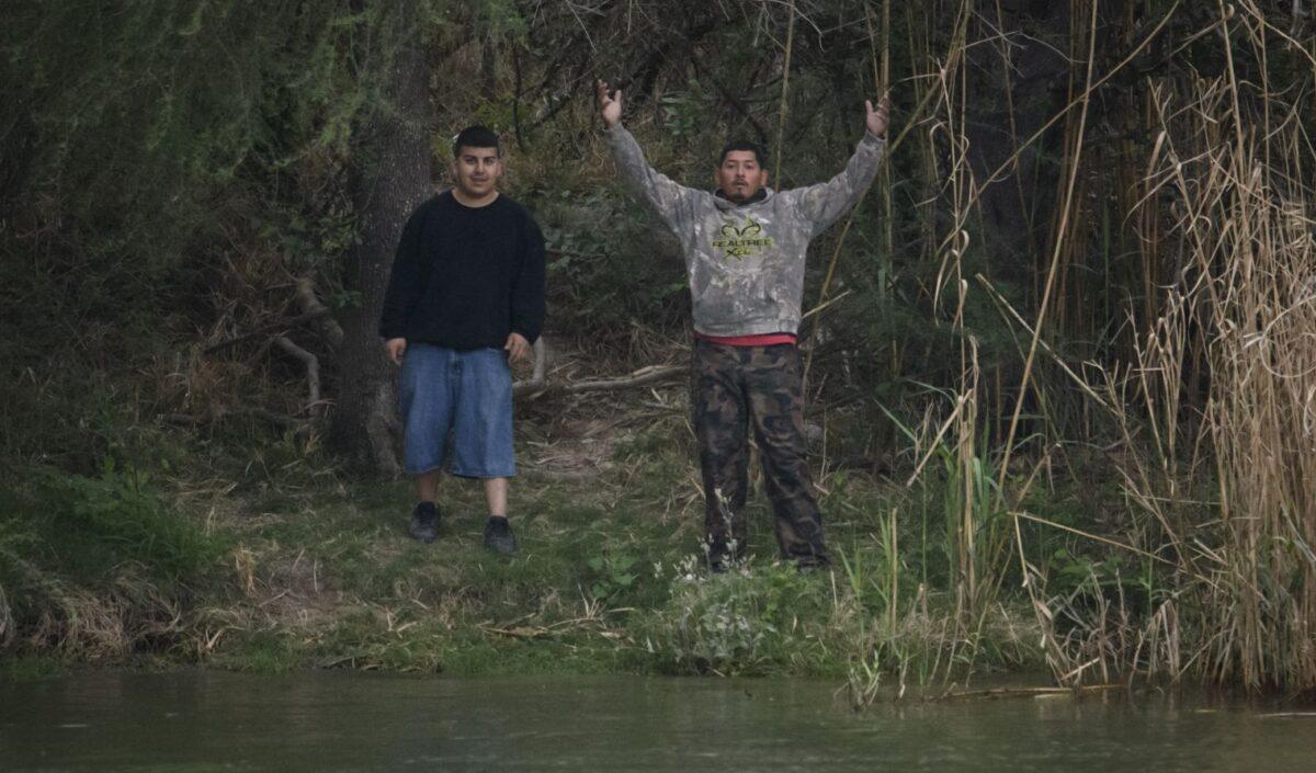 'Coyote' people smugglers gesture as they stand on the Mexico side of the Rio Grande River near the U.S. border city of Roma on March 28, 2021. (Ed Jones/AFP via Getty Images)