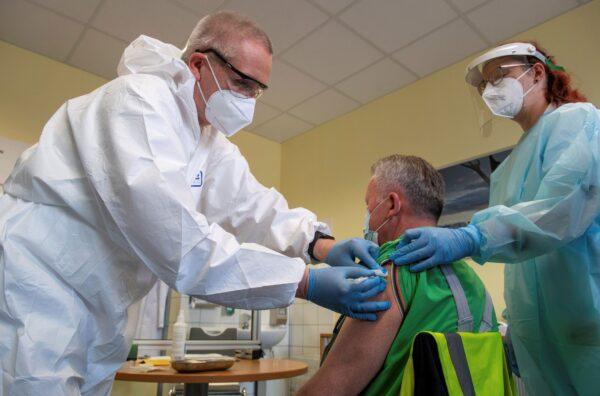 Harry Hoffmann (L), a Volkswagen company doctor, and nurse Nicolle Sprotte (R), vaccinate Steffen Martin, an employee at the Volkswagen Saxony plant, with the AstraZeneca vaccination in Zwickau, Germany, on March 30, 2021. (Hendrik Schmidt/dpa via AP)