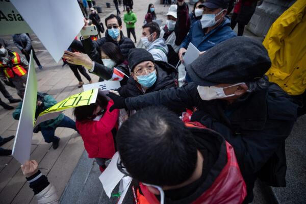 A man holding a sign that says "Hold CCP Liable Stop Asian Hate" is obstructed by people at an anti-Asian hate rally in Vancouver on March 28, 2021. (The Canadian Press/Darryl Dyck)