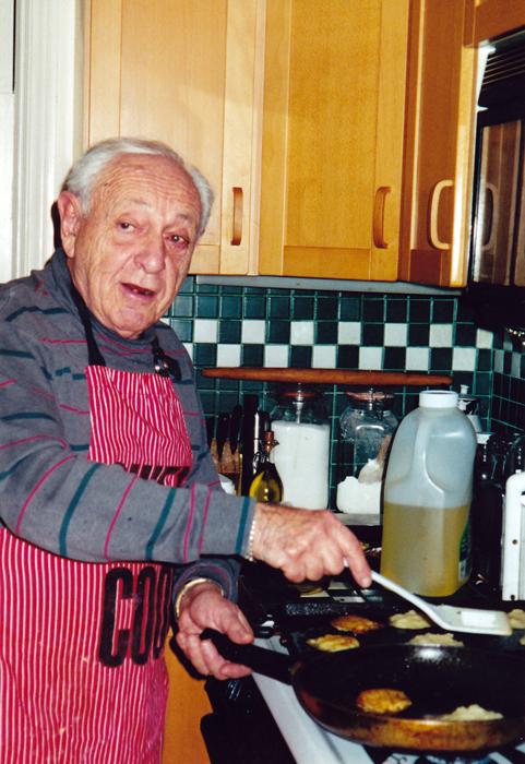The author's late father frying latkes in his kitchen. (Courtesy of Sandra Banas)