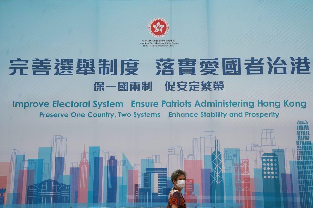 A woman walks past a government advertisement promoting Hong Kong electoral reforms, following Chinese parliament's approval of a new electoral system reform plan, in Hong Kong on March 30, 2021. (Lam Yik/Reuters)