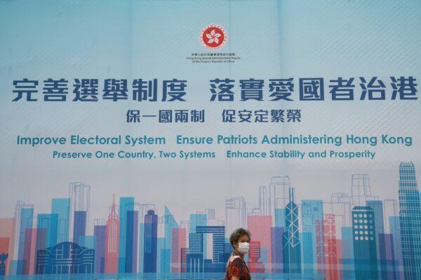 A woman walks past a government advertisement promoting Hong Kong electoral reforms, following Chinese parliament's approval of a new electoral system reform plan in Hong Kong on March 30, 2021. (Lam Yik/Reuters)
