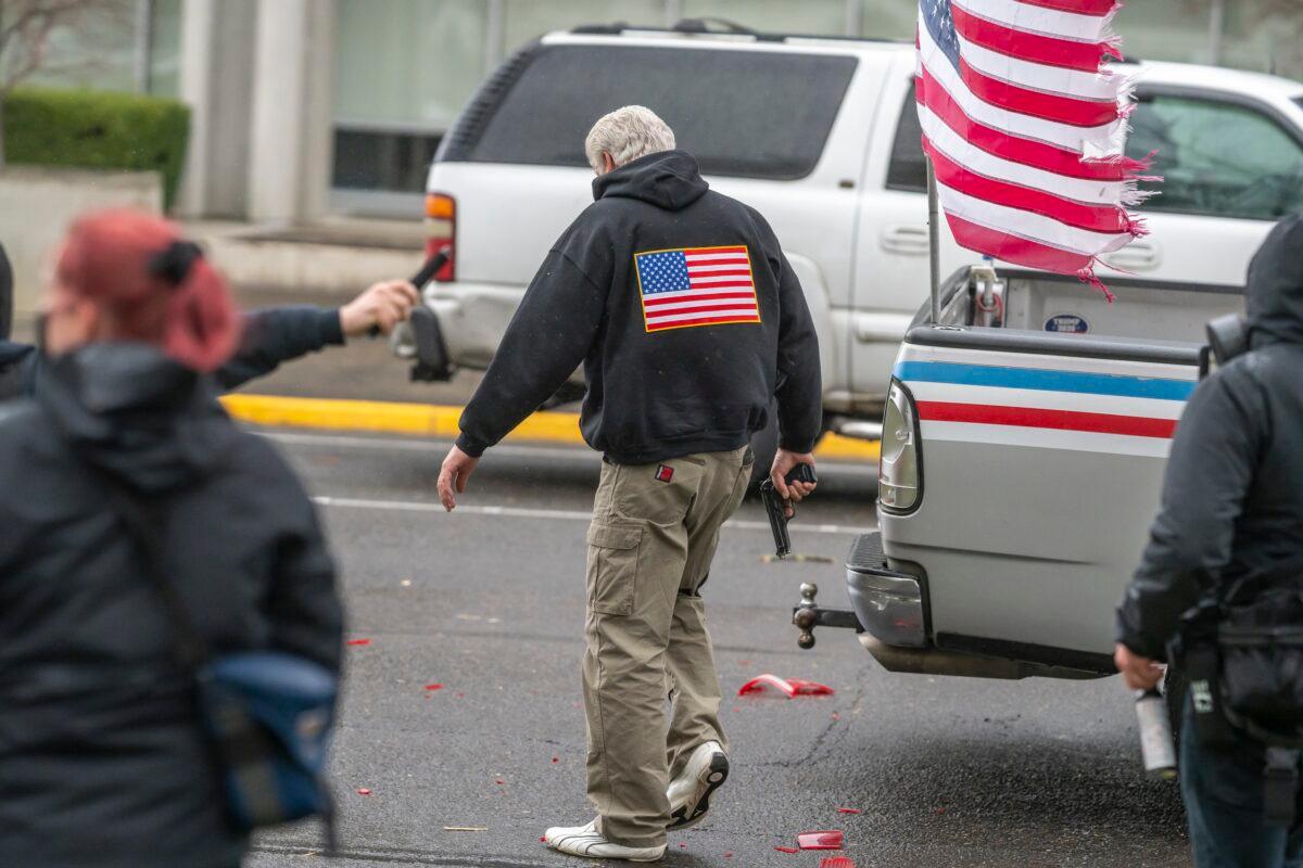 A driver pulls a handgun at Antifa members after they smashed his truck lights, in Salem, Ore., on March 28, 2021. (Nathan Howard/Getty Images)