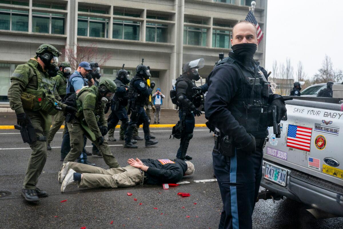 Law enforcement officers detain a man who pulled a handgun on a crowd after they broke his truck lights, in Salem, Ore., on March 28, 2021. (Nathan Howard/Getty Images)