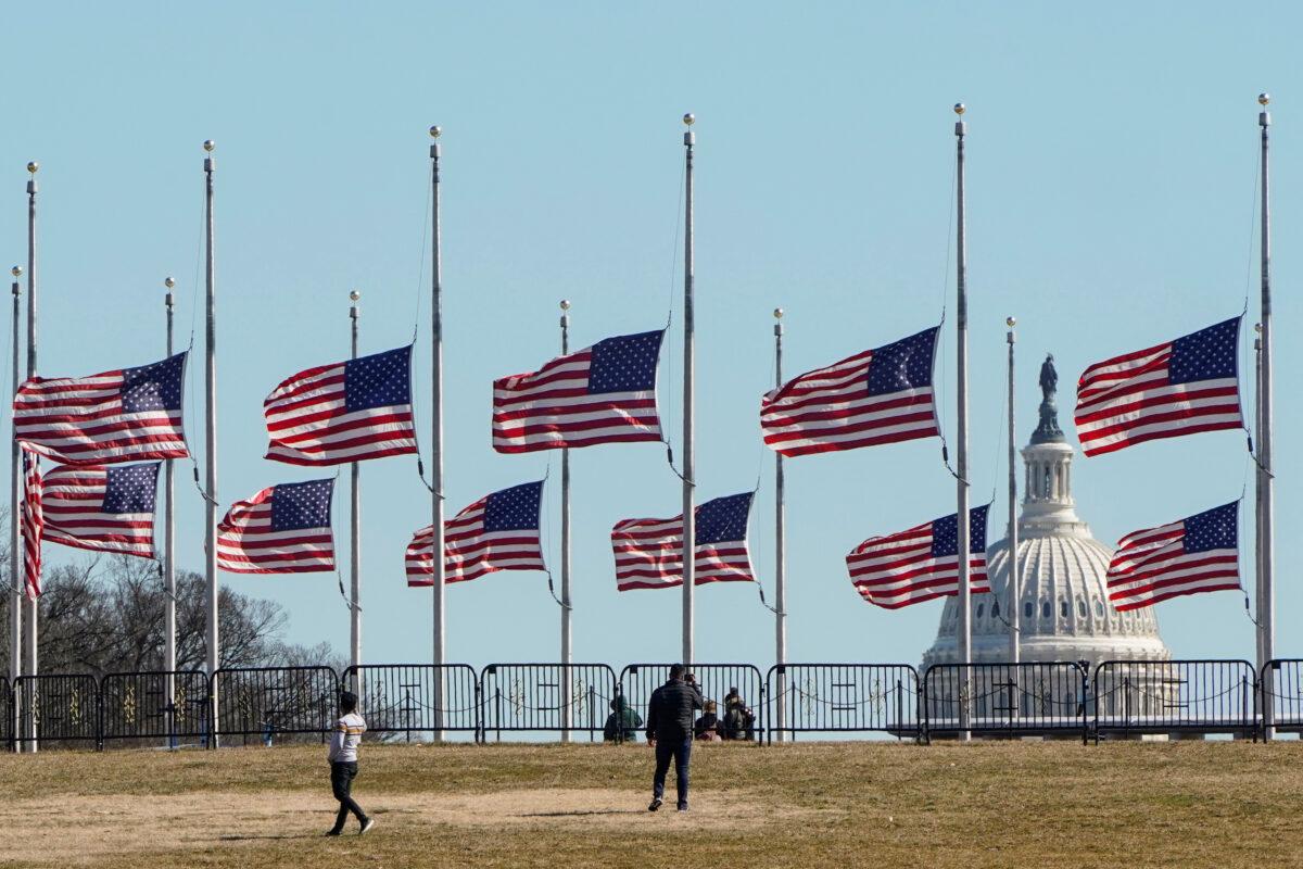 People walk past flags flying at half staff at the Washington Monument in memory of 500,000 deaths due to COVID-19 in Washington on Feb. 24, 2021. (Joshua Roberts/Reuters)