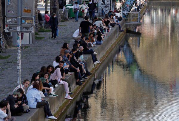 People enjoy the warm weather sitting along the Canal Saint-Martin in Paris amid the CCP virus outbreak in France, on March 31, 2021. (Gonzalo Fuentes/Reuters)