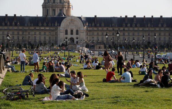 People enjoy the warm weather sitting on the grass near the Invalides in Paris amid the CCP virus outbreak in France, on March 31, 2021. (Gonzalo Fuentes/Reuters)