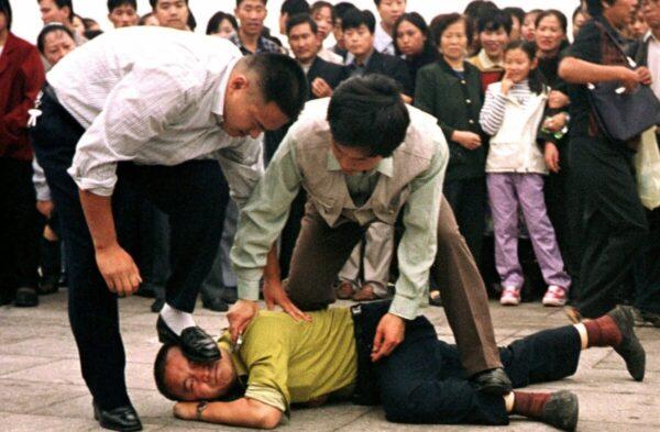 Police detain a Falun Gong protester in Tiananmen Square as a crowd watches in Beijing on Oct. 1, 2000. (AP Photo/Chien-min Chung)