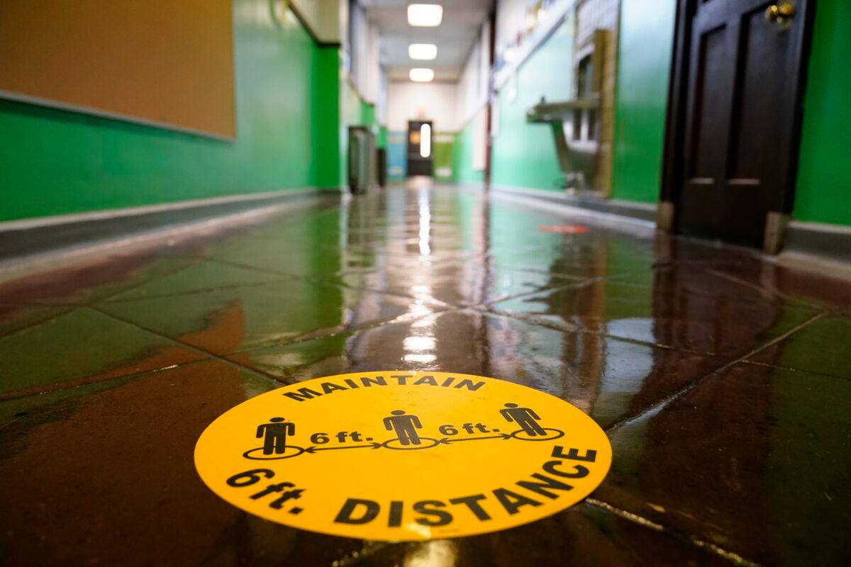 A social distancing reminder is posted on a hallway floor of Nebinger Elementary School in Philadelphia, Pa., on March 19, 2021. (Matt Rourke/AP Photo)