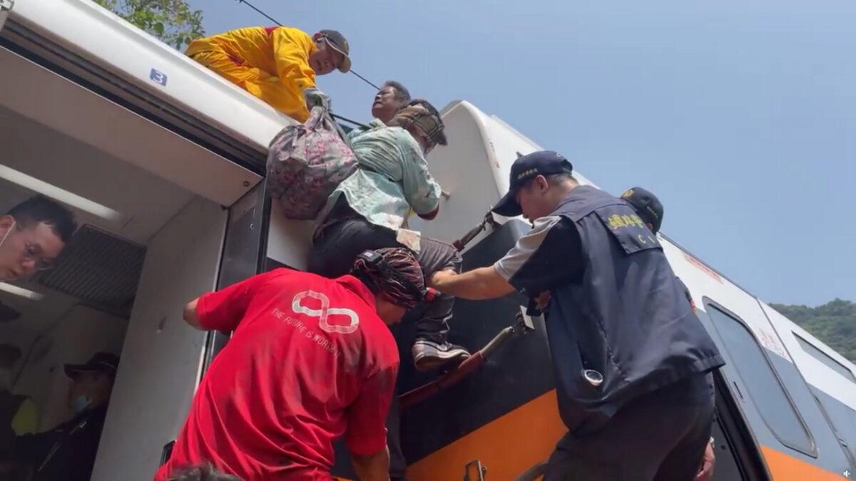 Rescue team help one of the stranded passengers down from the roof of a train which derailed in a tunnel north of Hualien, Taiwan, on April 2, 2021. (Screenshot/Facebook/Hualienfastnews via Reuters)