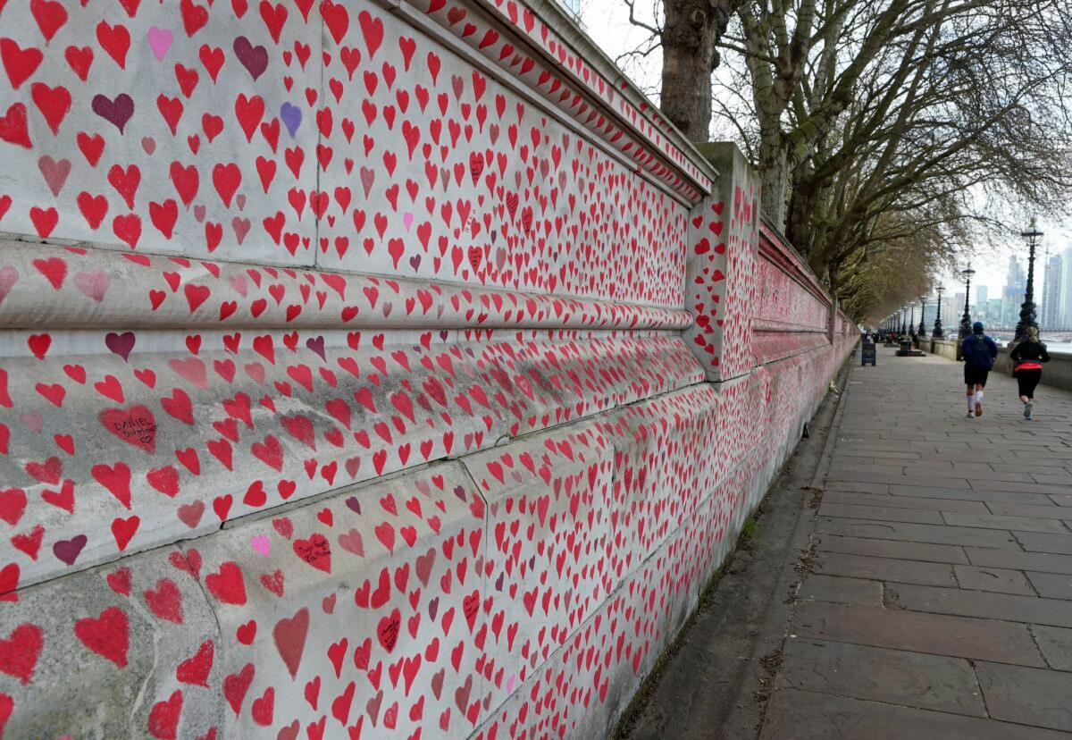 People jog past the 'The National COVID Memorial Wall' on the south bank of the Thames in front of St. Thomas' hospital and opposite the House of Parliament in London, on April 4, 2021. (Tony Hicks/AP Photo)