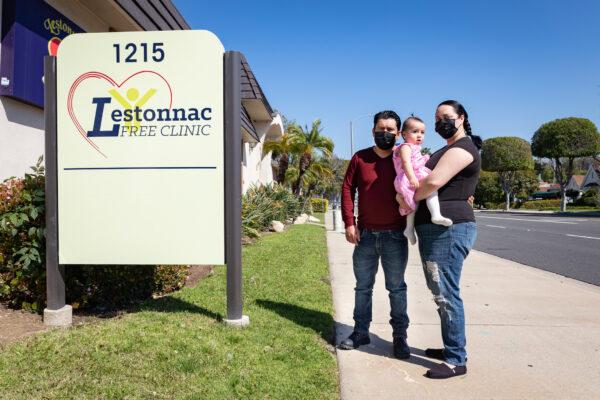 Israel Zuniga (L) stands with his family in front of the Lestonnac Free Clinic in Orange, Calif., on March 19, 2021. (John Fredricks/The Epoch Times)