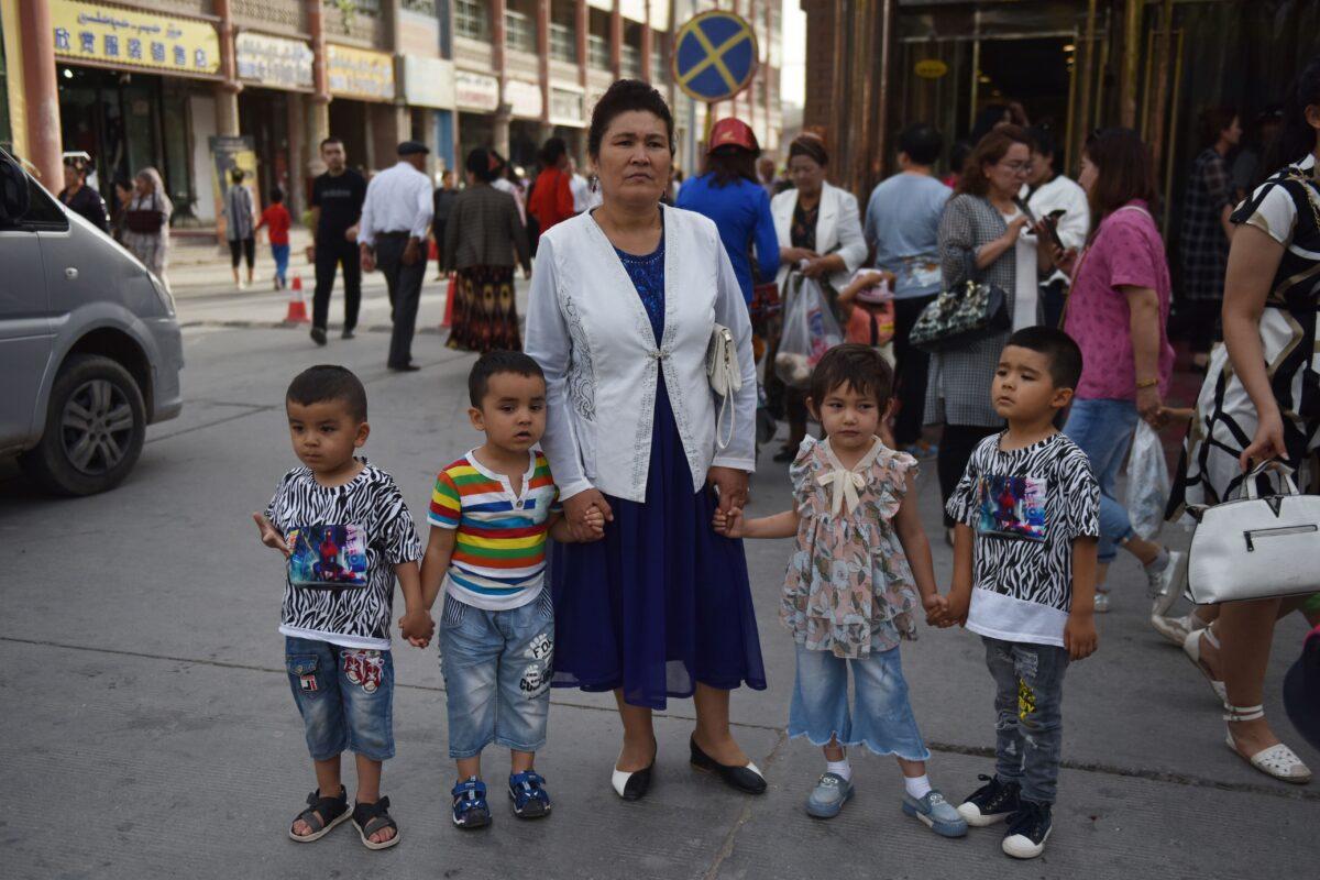 A Uyghur woman waits with children on a street in Kashgar in northwest China's Xinjiang region on June 4, 2019. (Greg Baker/AFP via Getty Images)