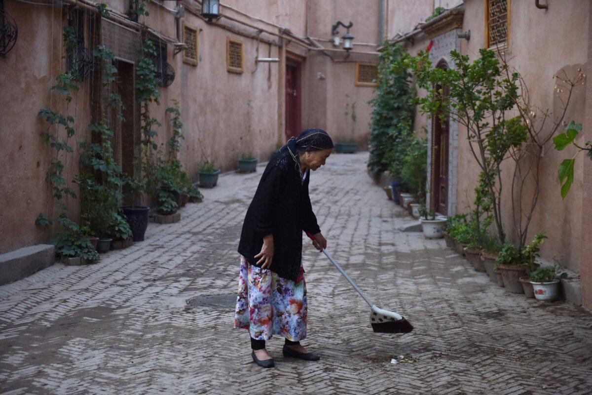 A Uyghur woman is cleaning a path in a restored section of the old city in Kashgar in China's northwest Xinjiang region on June 4, 2019. (Greg Baker/AFP via Getty Images)
