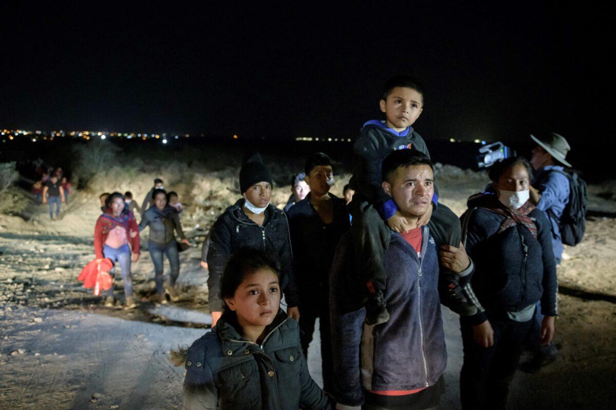 Immigrants who arrived illegally from across the Rio Grande river from Mexico make their way along a track towards a processing checkpoint set up by Border Patrol agents in the border city of Roma, Texas, on March 27, 2021. (Ed Jones/AFP via Getty Images)