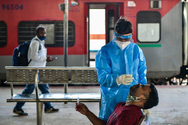 A health worker collects a sample from a passenger for an RT-PCR test at the Yesvantpur railway station in Bangalore, India, on Apr. 5, 2021. (Manjunath Kiran /AFP via Getty Images)
